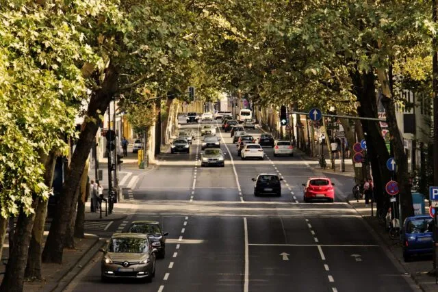 Stradă de oraș dimineața, cu frunze căzute și brumă pe trotuar