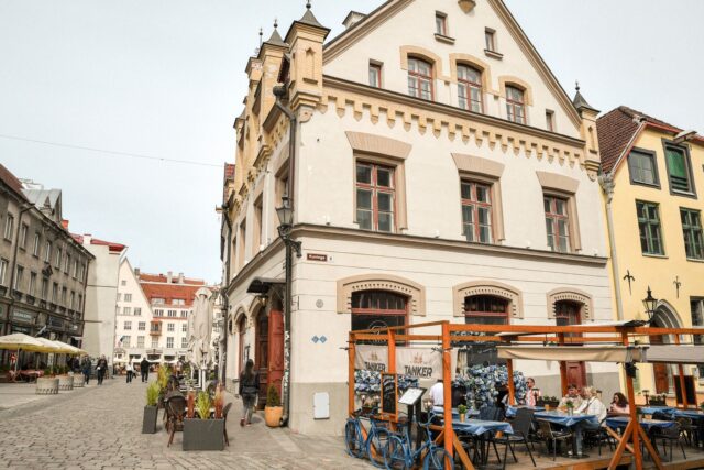Terasă de restaurant cu mese din lemn pe o stradă pietruită din centrul vechi, în lumina caldă a serii