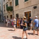 Ghid care prezintă istoria unei clădiri vechi unui grup mic de turiști, pe o stradă pietruită din centrul istoric