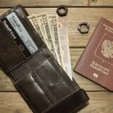 Portofel deschis cu carduri bancare și câteva bancnote, pe masa unei cafenele, lângă o hartă turistică
